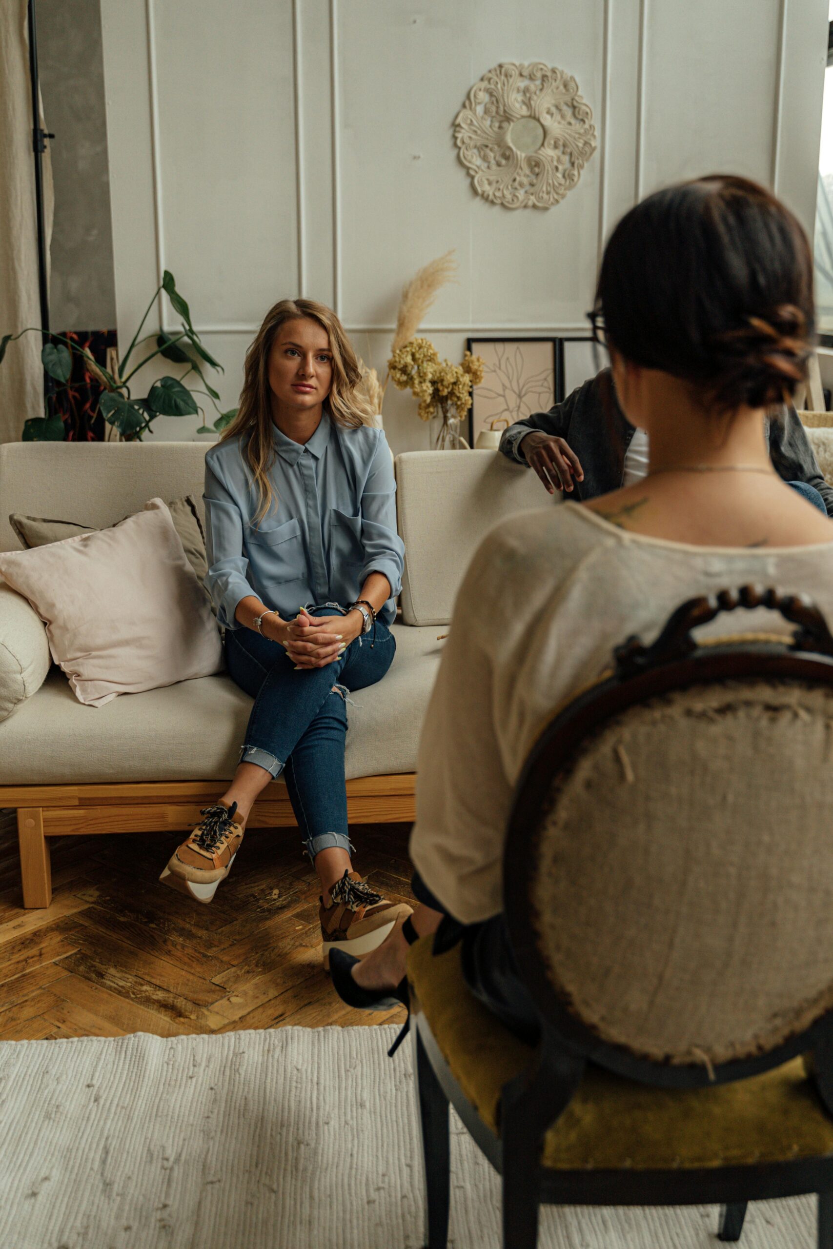 Woman therapist talking to a client on a sofa in a therapy office, representing an EMDR session